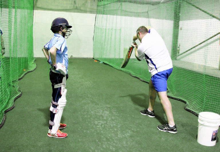 Cricket coach demonstrating bowling techniques during private training at Complete Cricket.